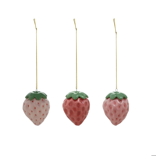 Three ceramic strawberry ornaments in light pink, rose, and mauve with green tops and gold string